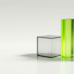 Three translucent glass objects of different shapes standing in a row on a clean reflective white floor: a solid cube, a tall narrow slab, and a thin wide sheet, two of them clear and softly frosted, one glowing with lime green